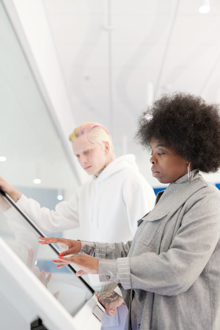 African American woman and Caucasian man using a touchscreen in a stylish setting.